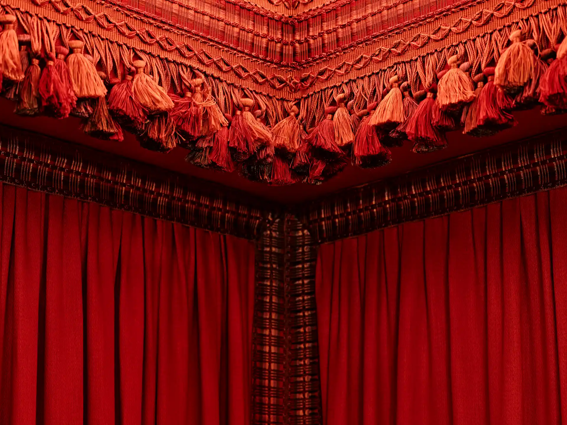 The Fifth Avenue Hotel 7 Red tassel-trimmed canopy with pleated curtains and ornate fringe detailing in luxurious hotel room