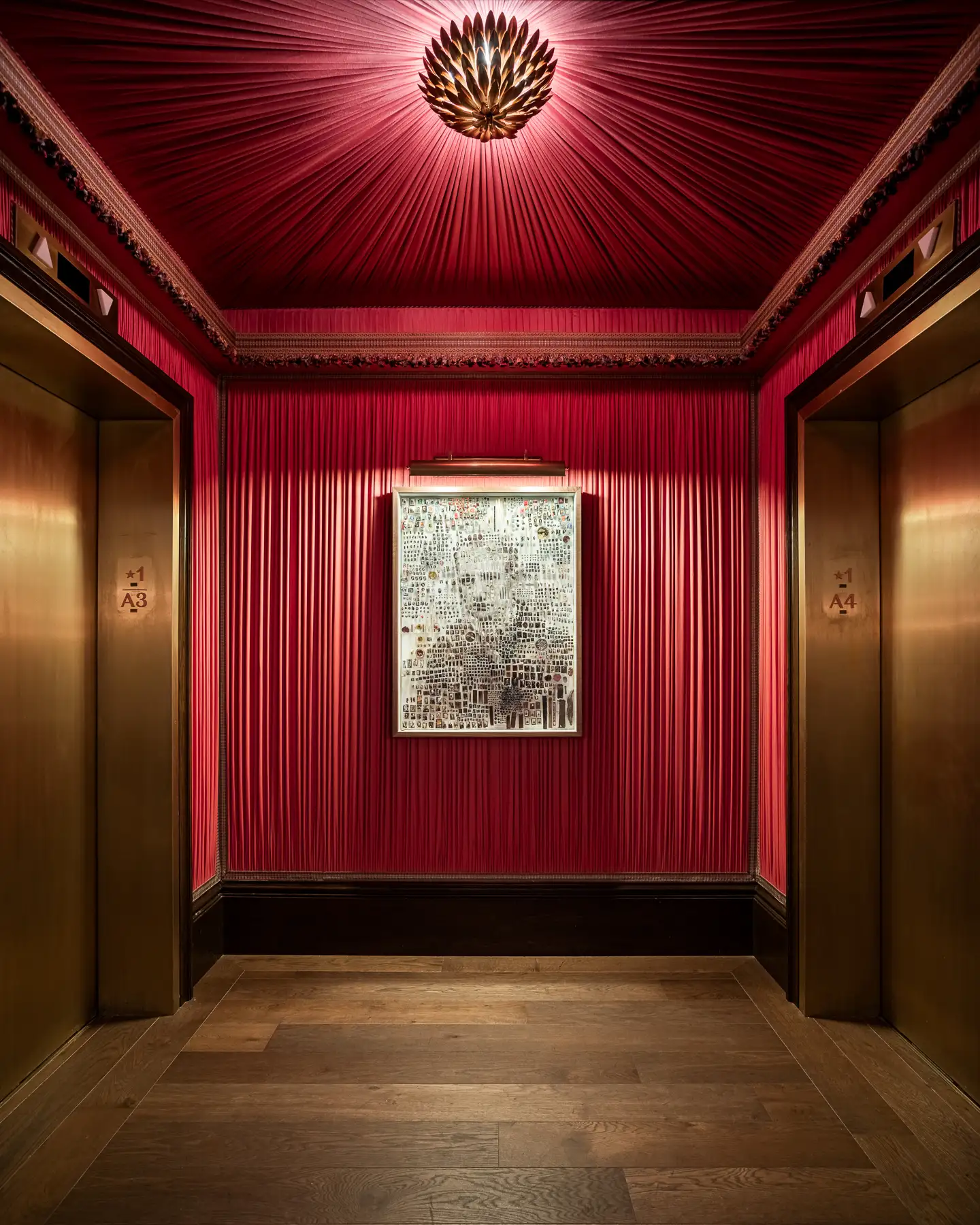 The Fifth Avenue Hotel 6 Red fabric elevator lobby at The Fifth Avenue Hotel with gold doors, floral ceiling light, and abstract artwork