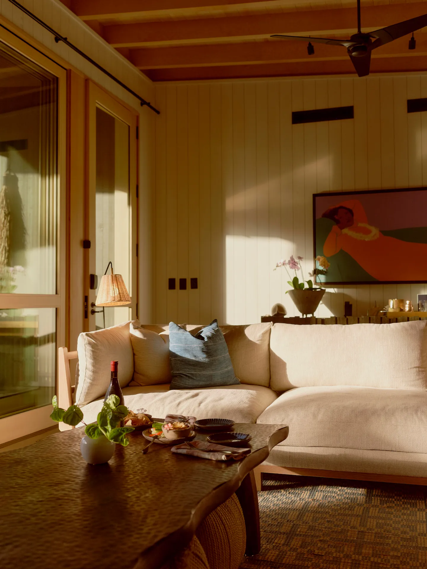 Cozy living room at Rosewood Kona Village with beige sofa, rustic wood table, and sunset wine setup.