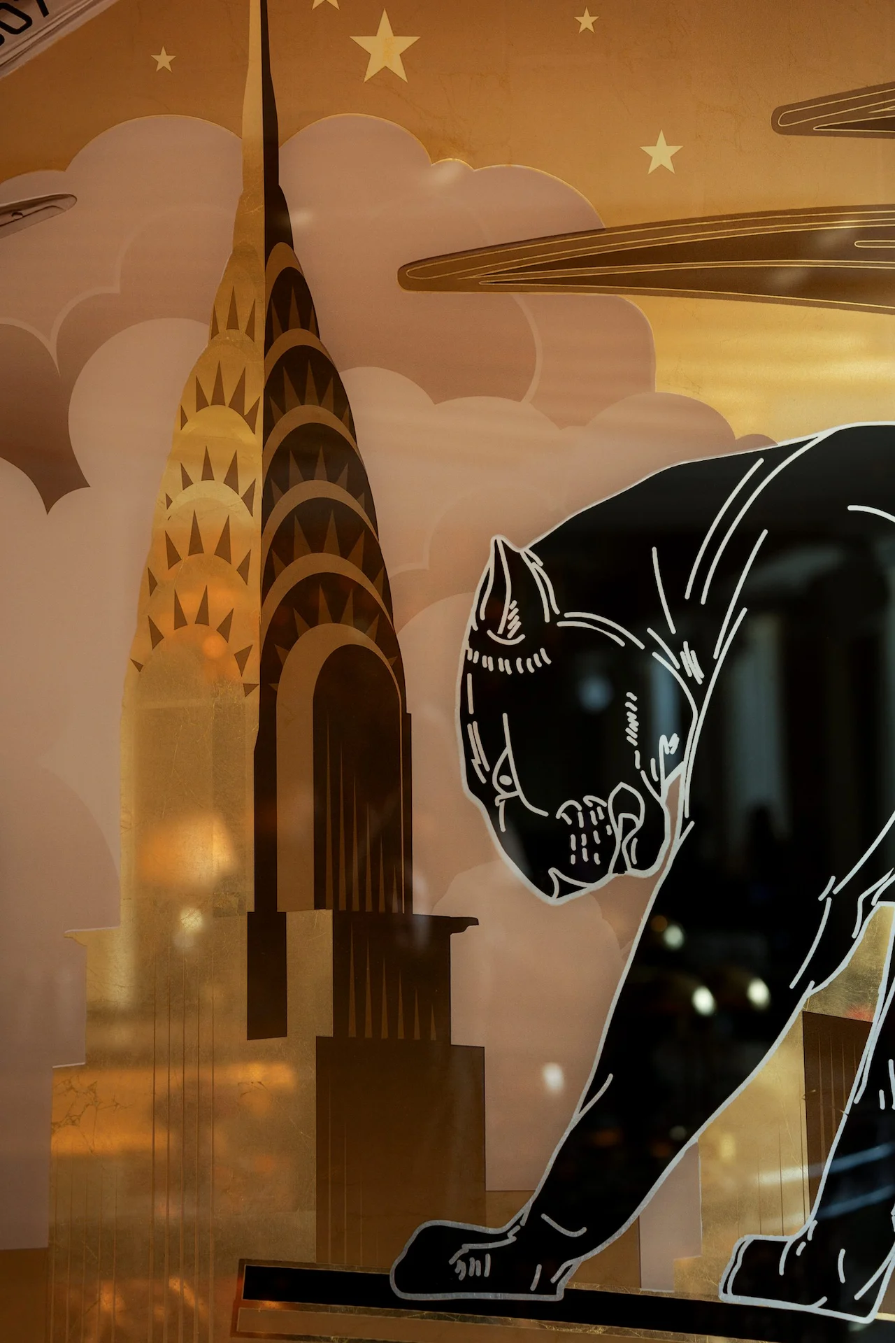 Art Deco mural of a stylized skyscraper with clouds and stars, beside a crouching black panther silhouette.