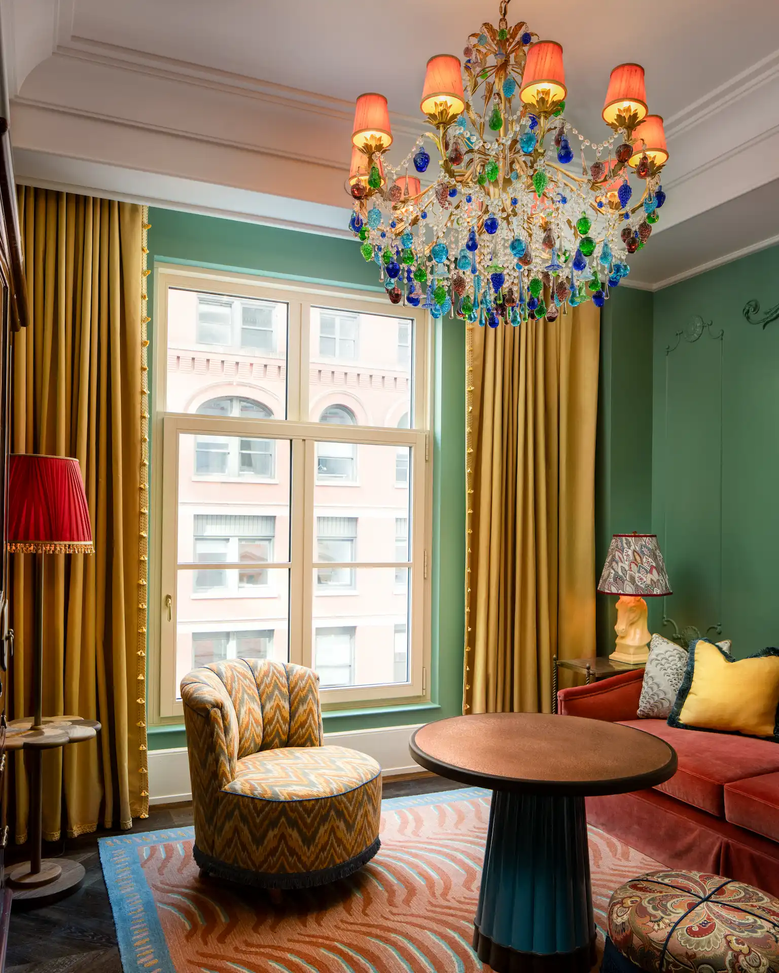 The Fifth Avenue Hotel 5 Colorful living room at The Fifth Avenue Hotel with crystal chandelier, patterned furniture, and yellow curtains