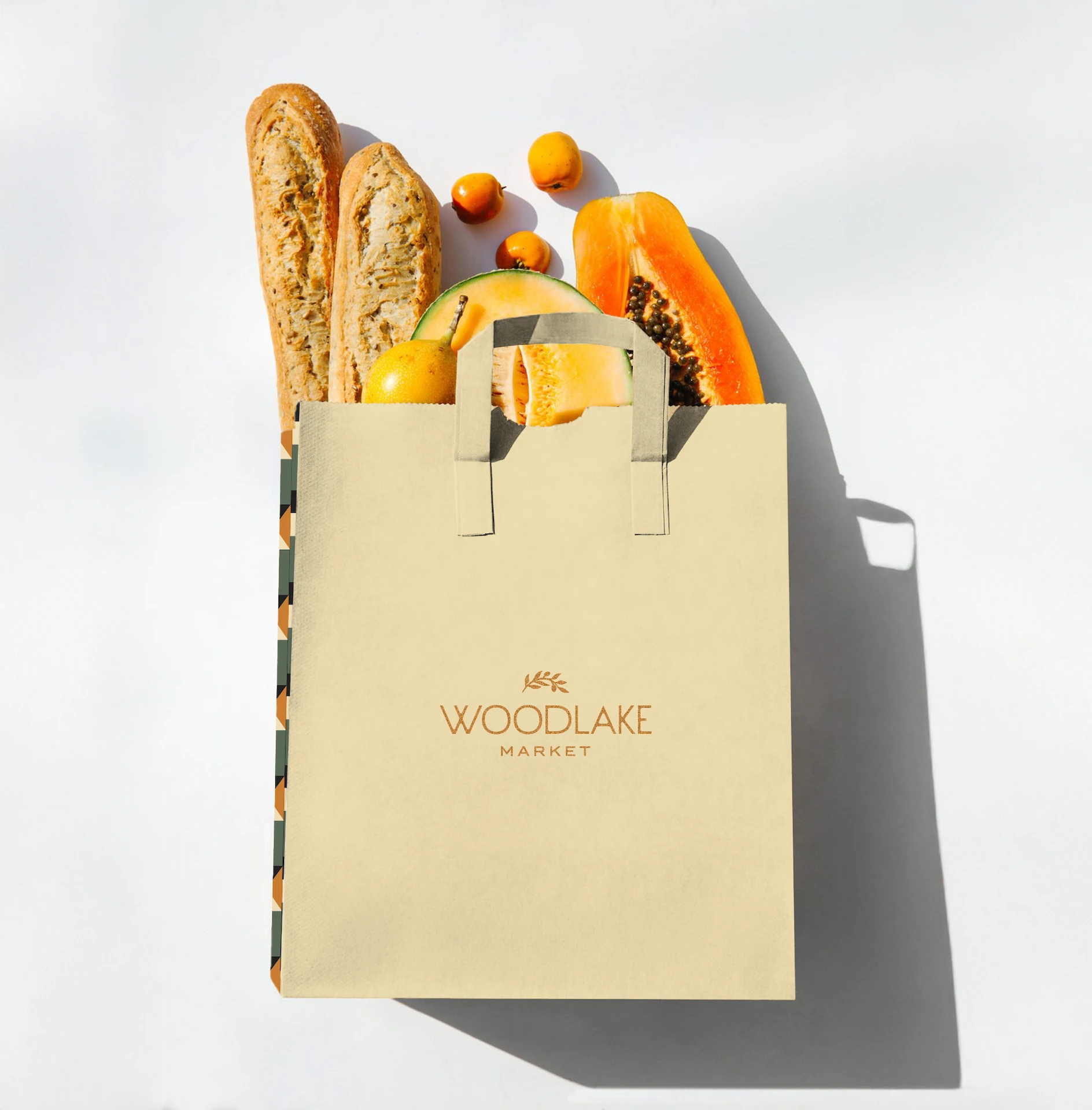 Woodlake Market 6 Beige grocery bag labeled Woodlake Market, filled with fresh produce including baguettes, papaya, and cantaloupe.