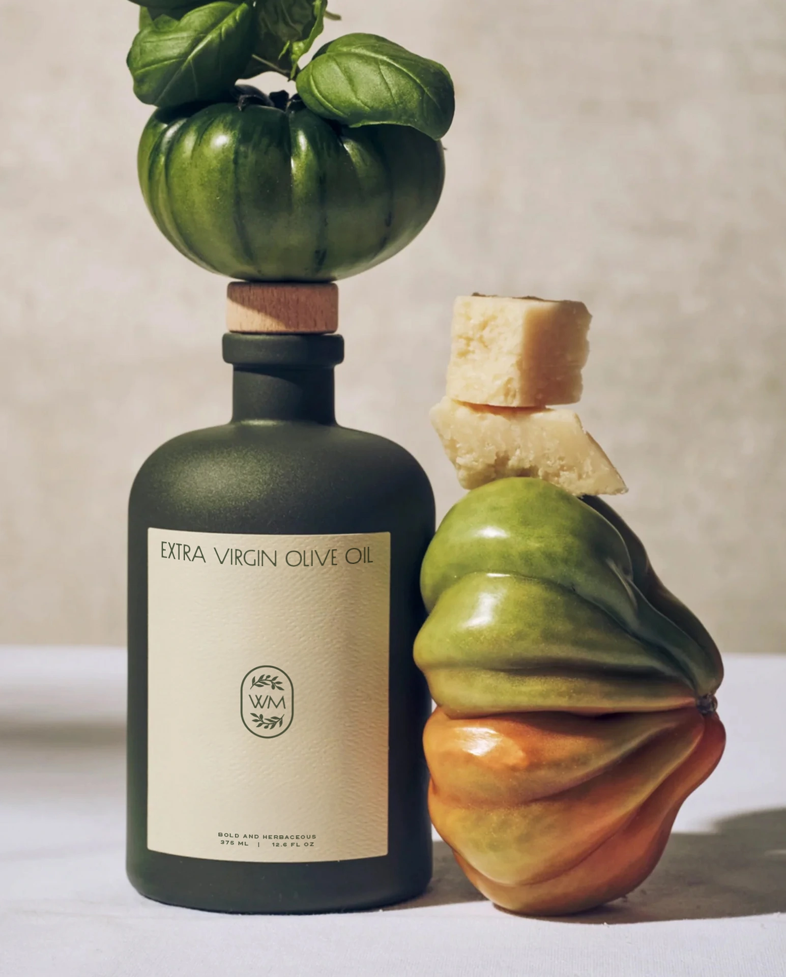 Branding by Spherical 16 Bottle of extra virgin olive oil styled with heirloom tomatoes, basil leaves, and stacked cheese pieces