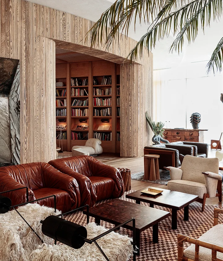 Eclectic living room with leather sofas, bookshelf, palm frond, and Mexican Style book on table.