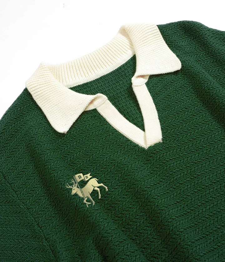 Branding by Spherical 19 Green knit sweater with cream V-neck and embroidered deer holding flags labeled B and B.