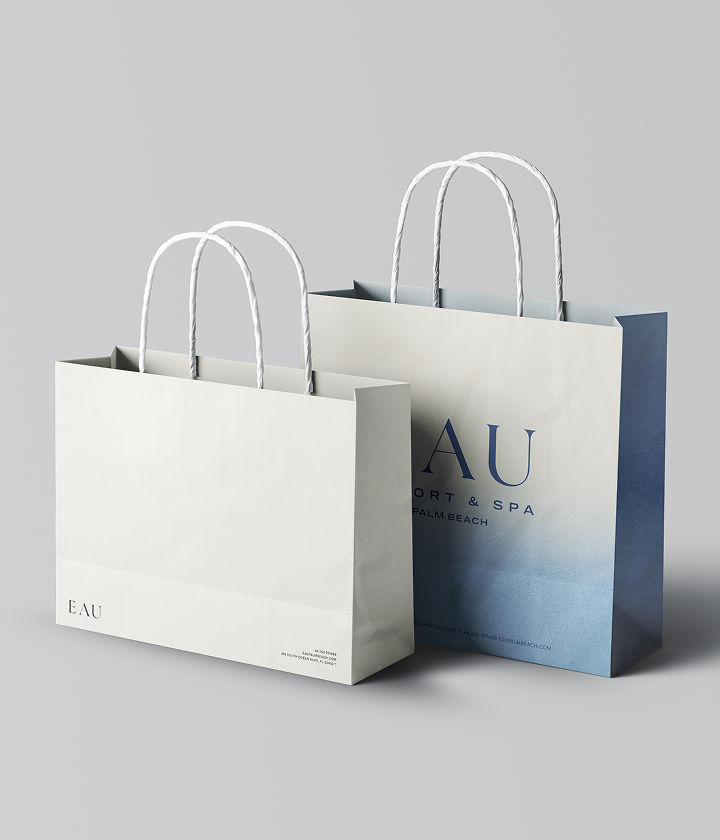 Branding by Spherical 21 Two branded Eau Palm Beach Resort & Spa shopping bags with rope handles on a neutral background.