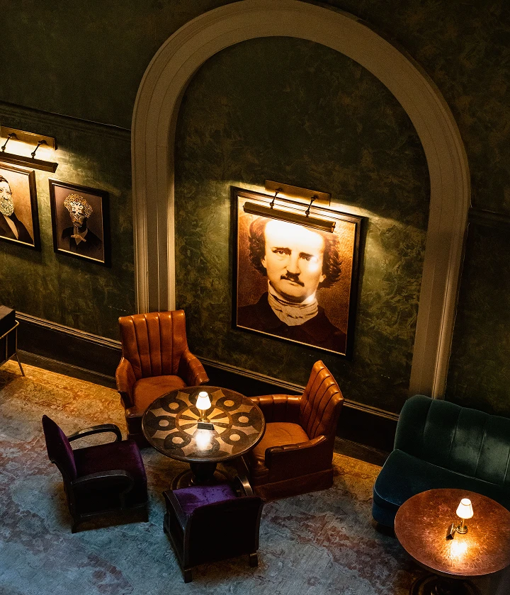 Dimly lit arched wall with framed portraits illuminated by warm picture lights.