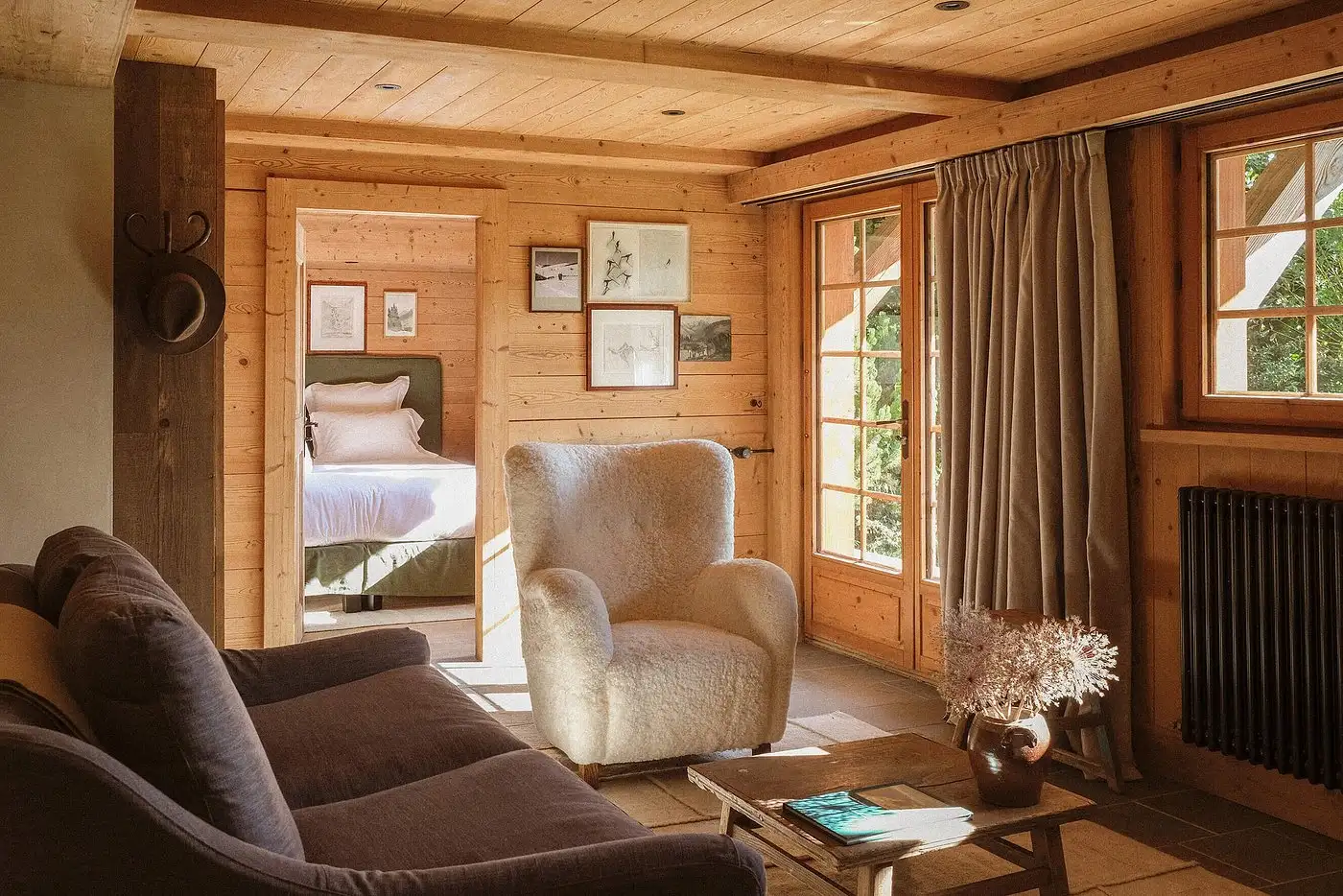 Rustic living room in Alpaga suite at Baumier with wood paneling, plush seating, and mountain view window