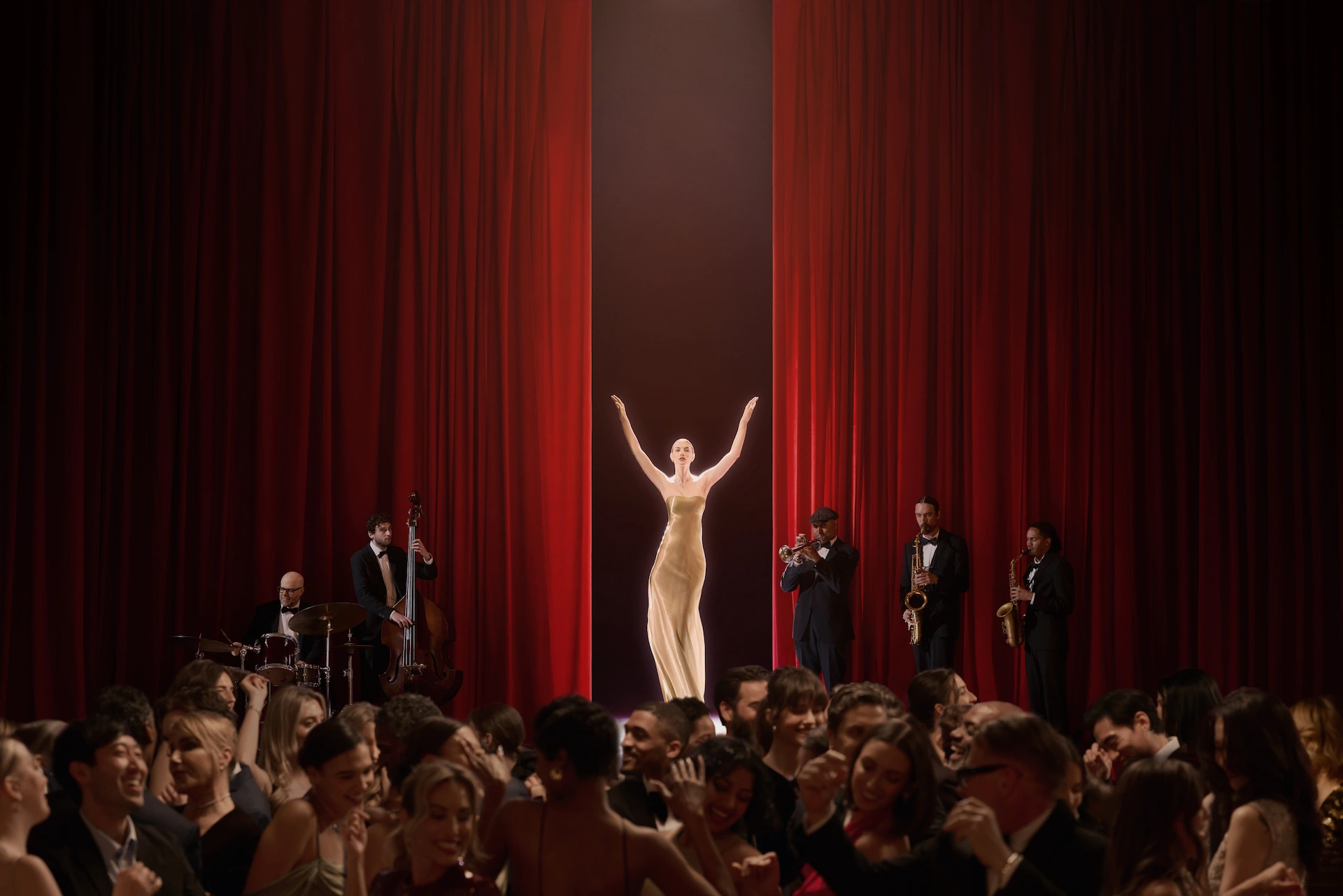 Singer in gold gown on stage with jazz band, red curtains, and crowd dancing at an elegant evening event.