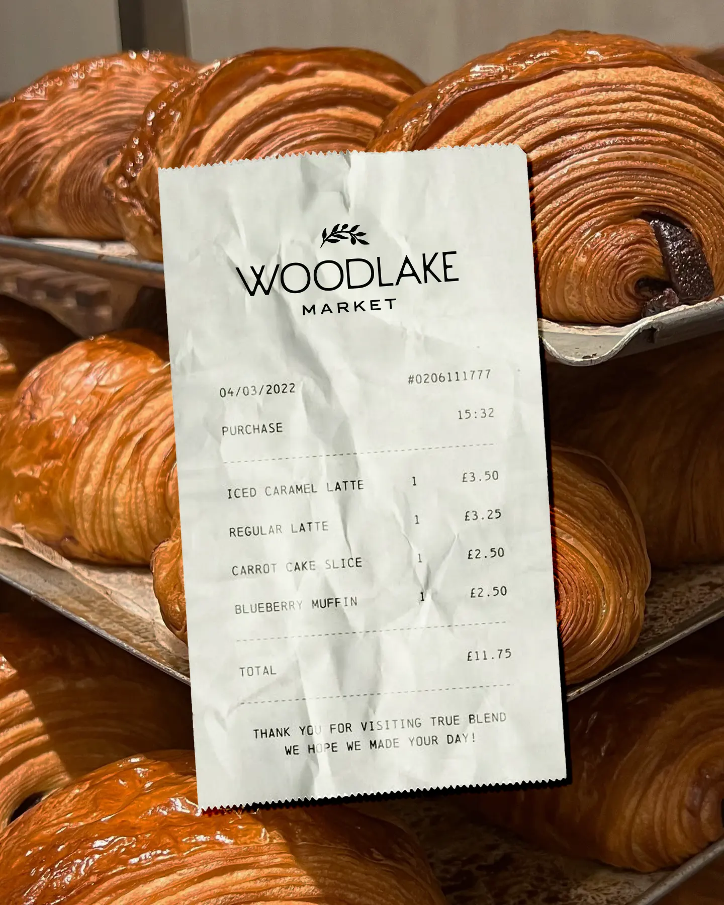 Woodlake Market 7 Receipt from Woodlake Market held in front of tray of fresh chocolate croissants; includes itemized café purchases.