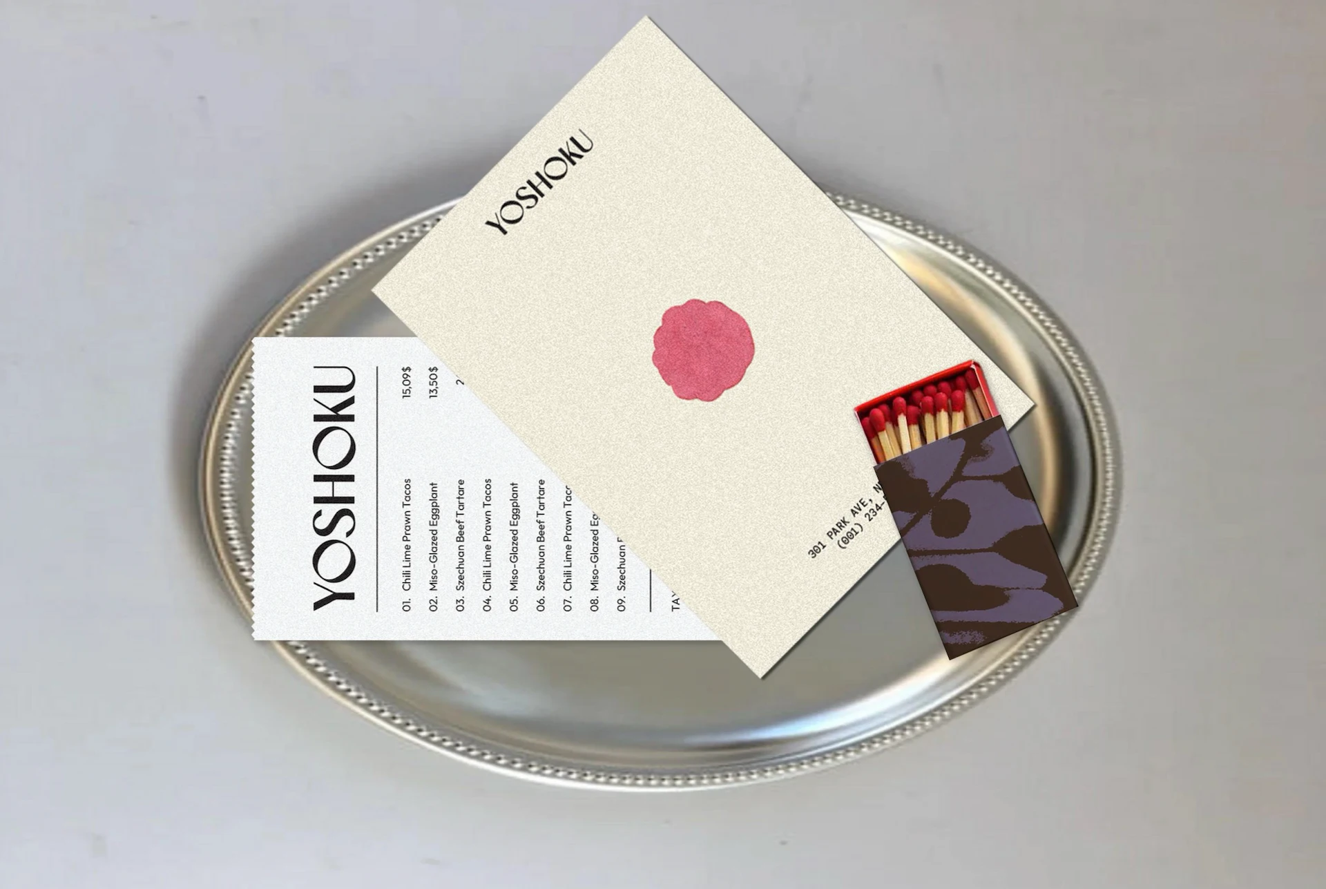 Silver tray with YOSHOKU menu, business card, and matchbox featuring red-tipped matches and floral design.