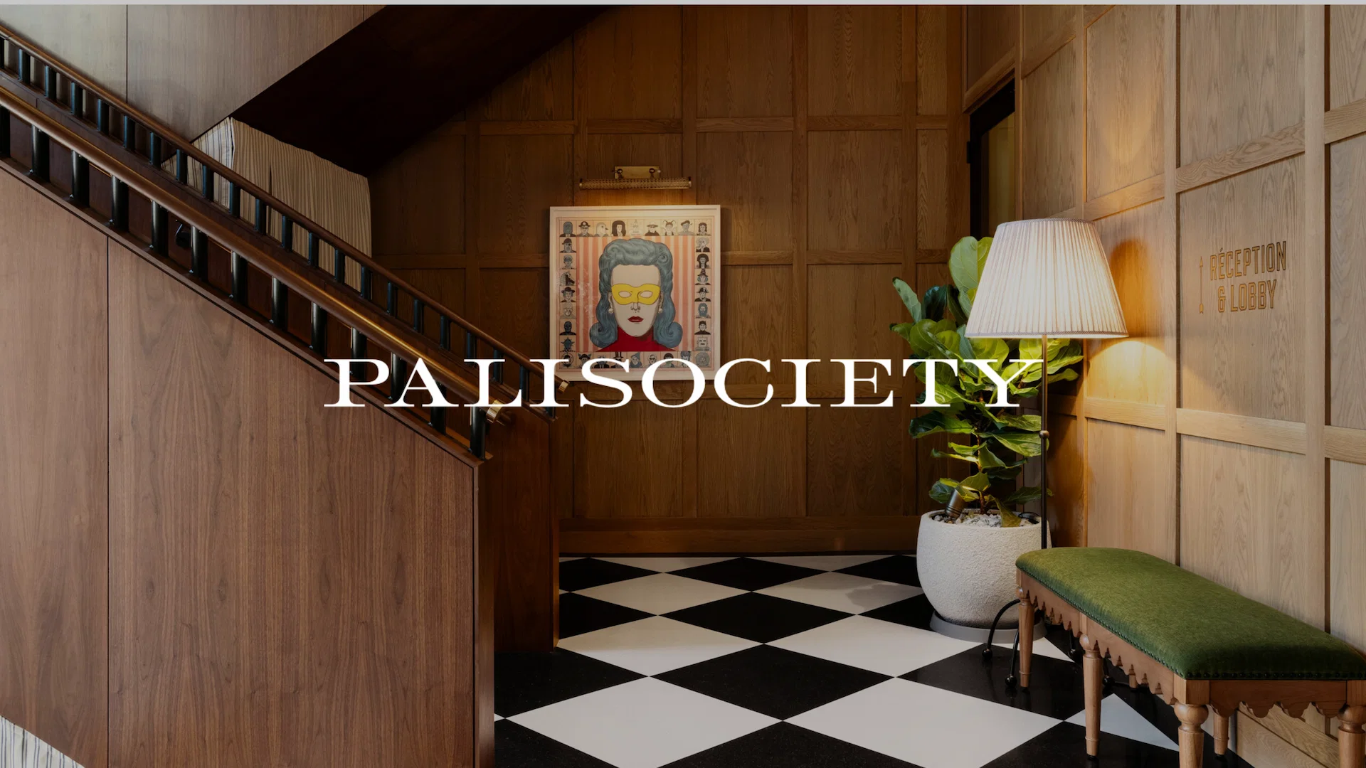 Palisociety 1 Hotel lobby with wood-paneled walls, checkered tile floor, green bench, and PALISOCIETY branding.