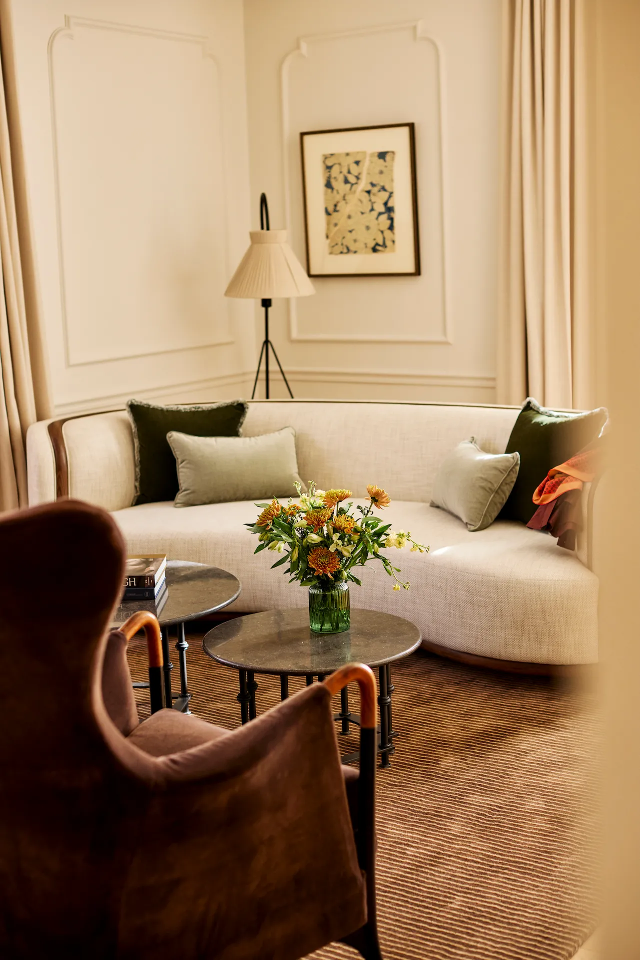 Elegant sitting area at The Bellevue Hotel with curved beige sofa, floral arrangement, and soft natural light.